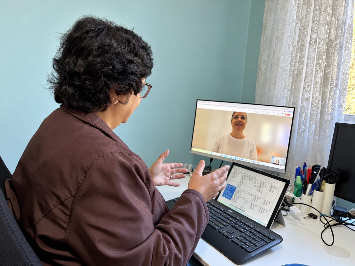 Anahita gesturing as she explains a point to a smiling student on a video call