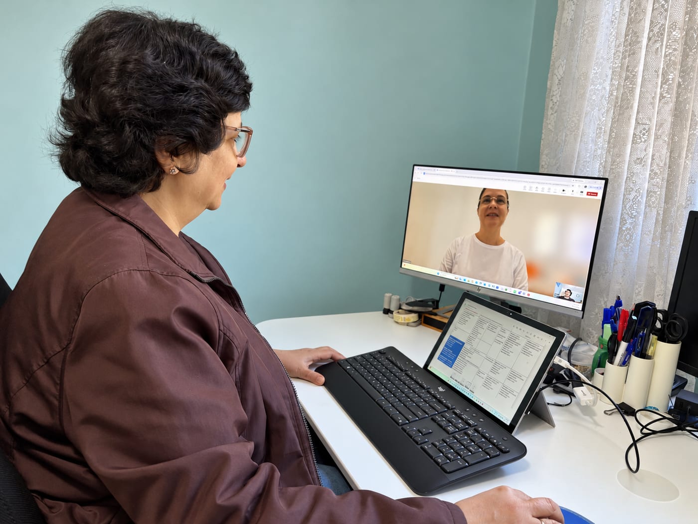 Anahita at her desk with a student on screen and lesson notes open on a tablet
